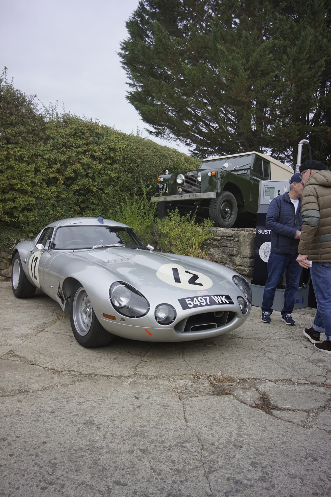 Silver lightweight Jaguar E-Type racer, number 12, outside the Classic Motor Hub